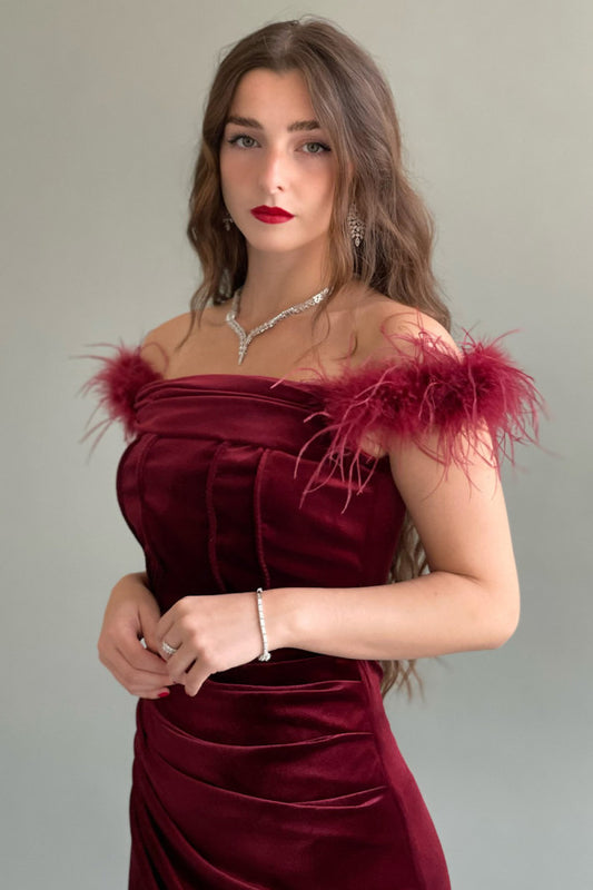 Off-the-shoulder velvet dress decorated with burgundy feathers