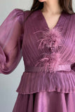 A mauve color dress decorated with feathers and a lulu on the chest